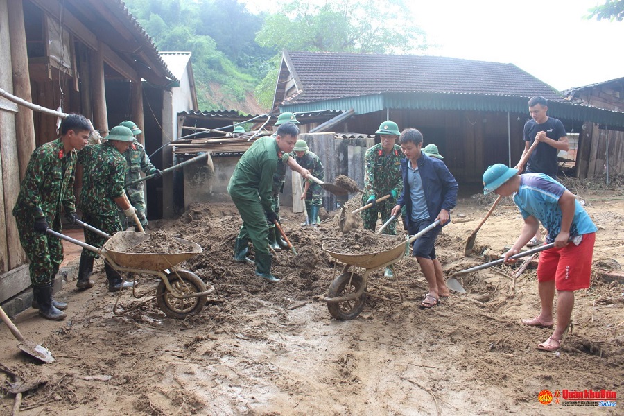 Bộ đội giúp bà con vận chuyển bùn đất ra khỏi nhà ở do cơn lũ để lại.