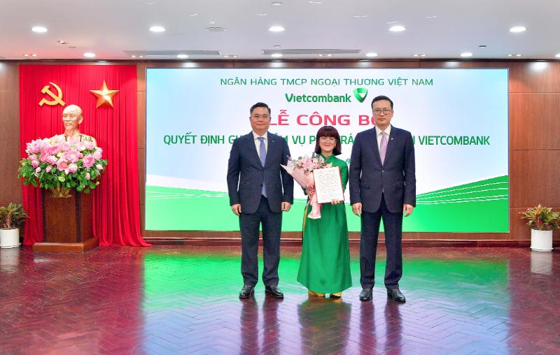 Đ/c Phạm Quang Dũng – Bí thư Đảng ủy, Chủ tịch Hội đồng Quản trị Vietcombank (bên phải) và Tổng Giám đốc Vietcombank Nguyễn Thanh Tùng (bên trái) trao Quyết định và tặng hoa chúc mừng bà Lê Thị Huyền Diệu- phụ trách Kế toán của Vietcombank.